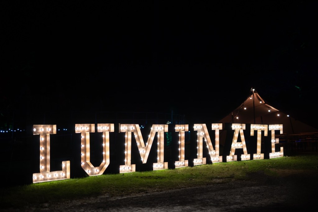 Large illuminated marquee letters spelling “LUMINATE” at night, photographed at Margam Country Park. Credit: www.clarehardingphotography.com