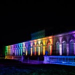 Classical Orangery building illuminated with rainbow lights at Luminate Wales, Margam Country Park. Credit: www.clarehardingphotography.com