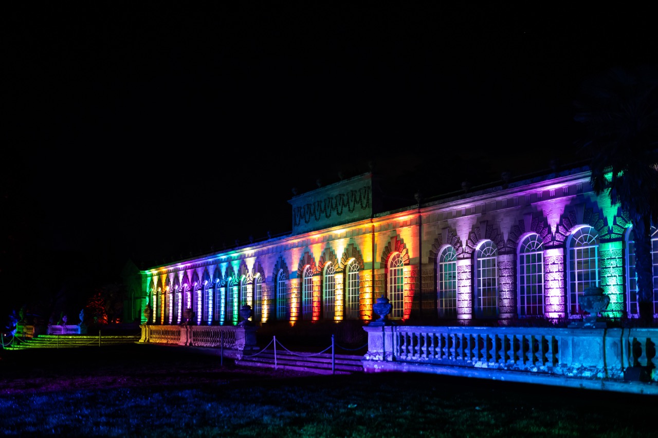 Classical Orangery building illuminated with rainbow lights at Luminate Wales, Margam Country Park. Credit: www.clarehardingphotography.com