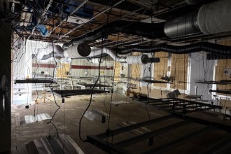 Interior of abandoned M&S store showing exposed ceiling, hanging cables, and metal frames — part of suspected cannabis setup.