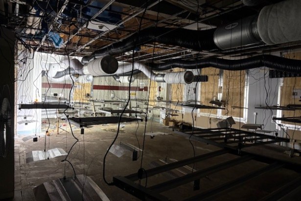 Interior of abandoned M&S store showing exposed ceiling, hanging cables, and metal frames — part of suspected cannabis setup.