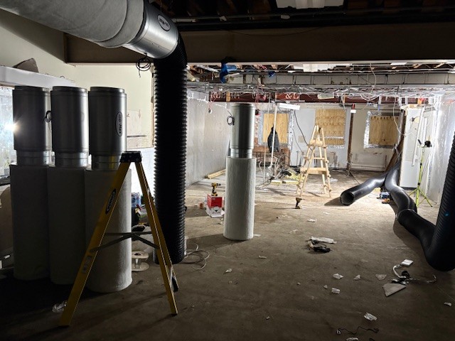 Wall-mounted ventilation ducts in unfinished room with exposed insulation — part of cannabis grow prep.