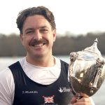 Ben Pritchard holding rowing trophy outdoors after winning European and world titles in 2025.