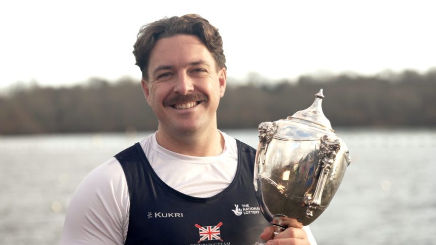 Ben Pritchard holding rowing trophy outdoors after winning European and world titles in 2025.
