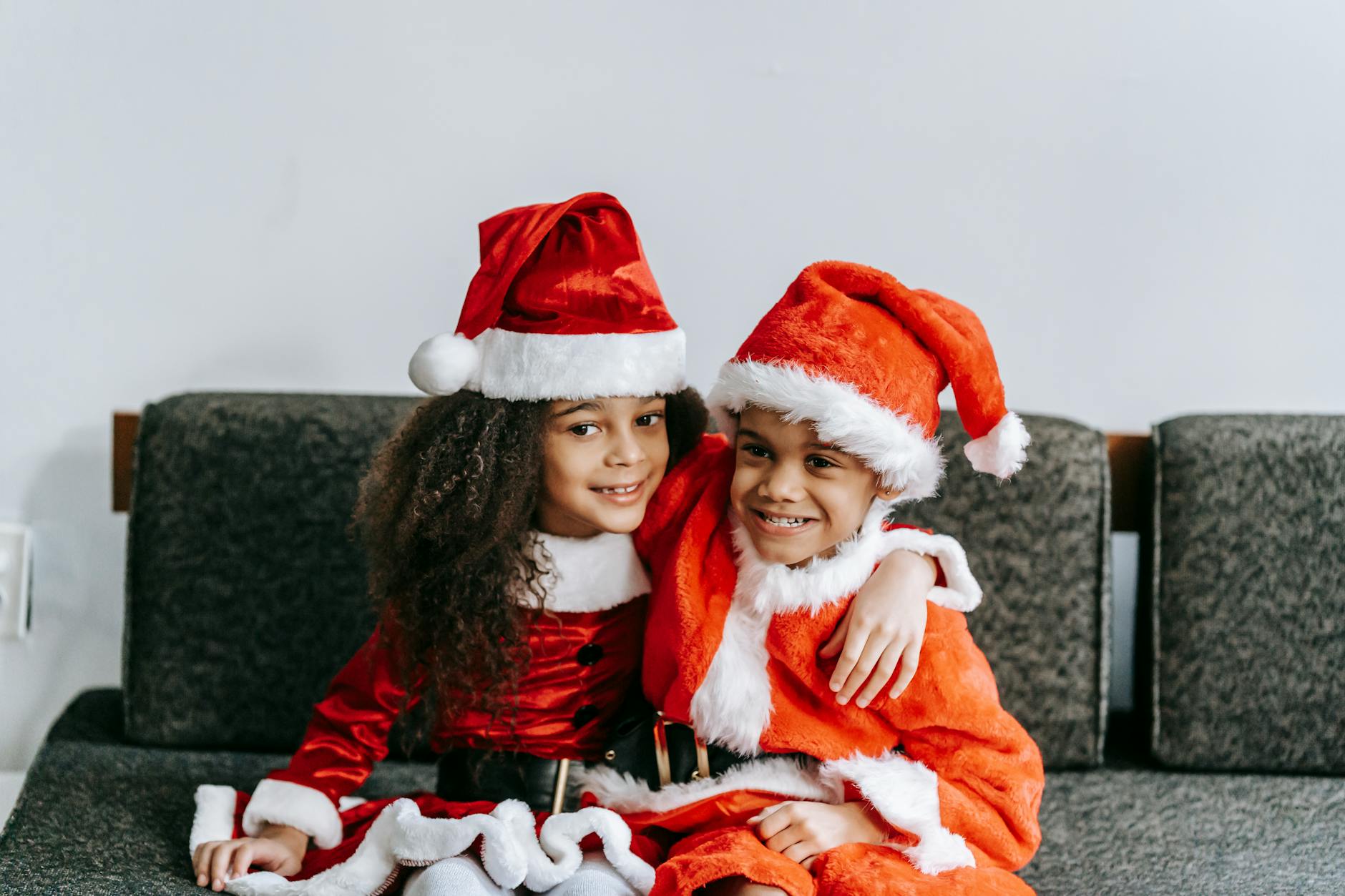 cheerful african american children embracing on sofa at home