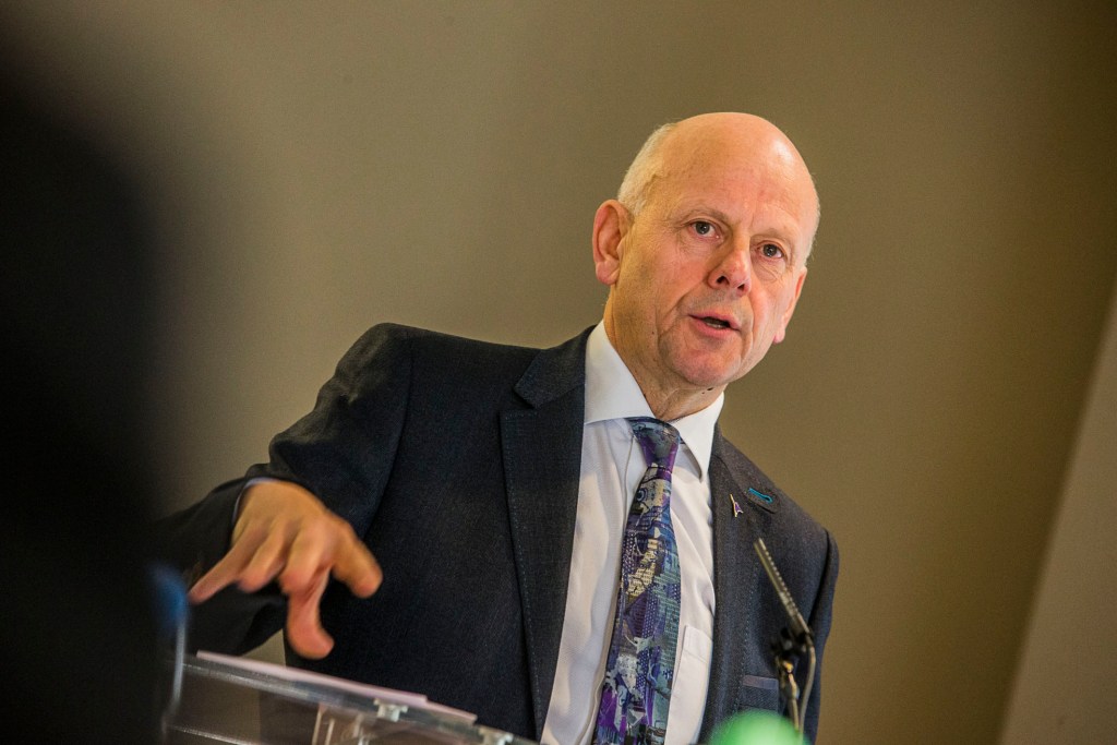 Mario Kreft speaking at a podium during a Care Forum Wales event.