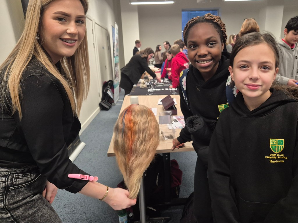 Cwm Glas Primary pupils watching a hair styling demonstration with a mannequin head at the Swansea Pledge launch event.