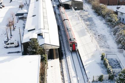 Overhead view of a TfW train at Llanelli station with snow covering the ground.
