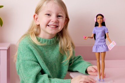 Penelope, aged five, holding the new autistic Barbie doll designed with input from autistic children.