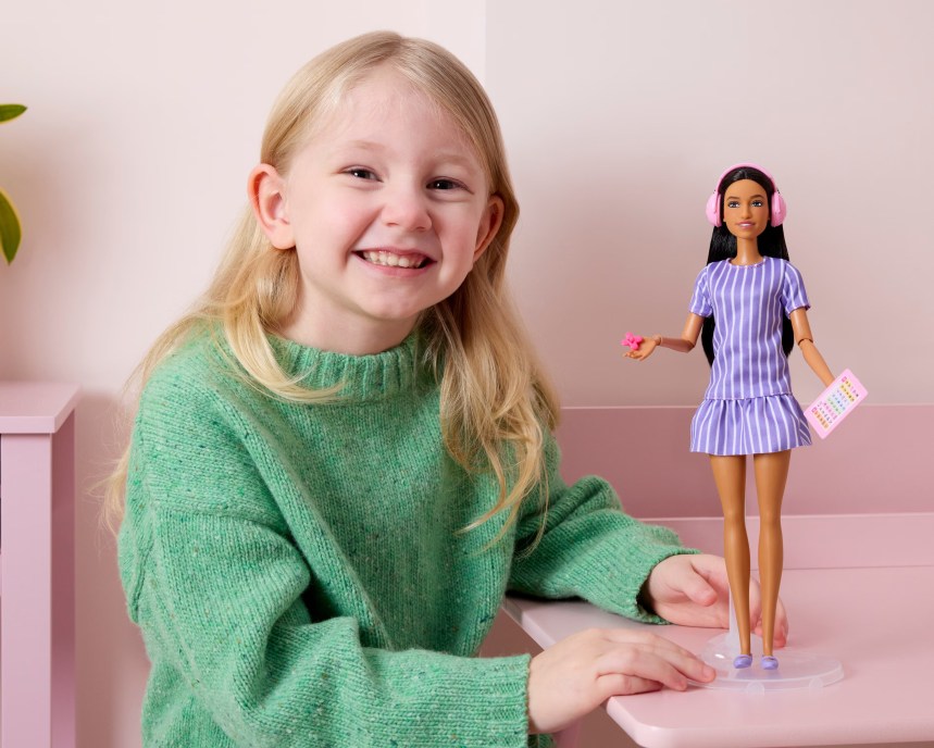 Penelope, aged five, holding the new autistic Barbie doll designed with input from autistic children.