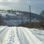 Snow-covered country road with tire tracks and hedgerows, photographed during winter conditions in Carmarthenshire.