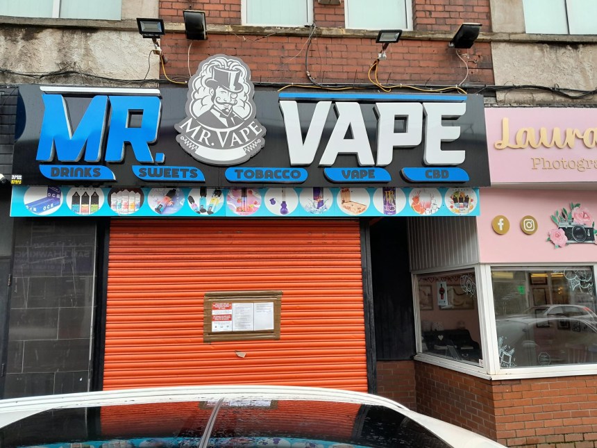 Red‑shuttered vape shop in Port Talbot with an official closure notice attached.