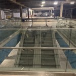 View down escalators inside empty Debenhams with exposed ceiling and construction fencing.