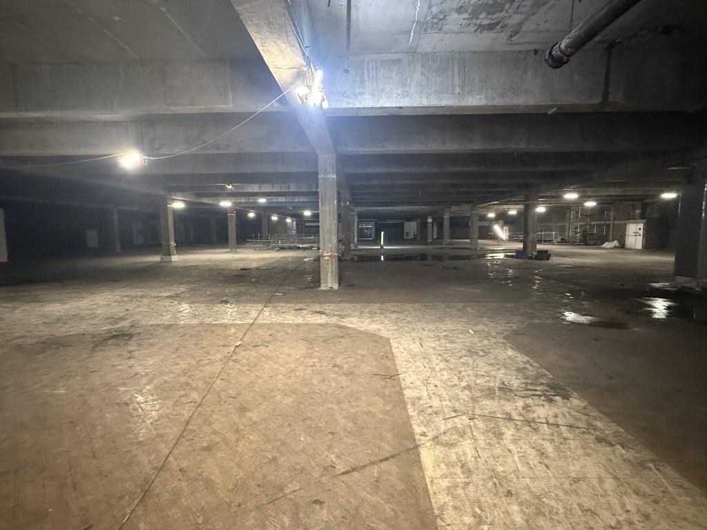 Open concrete interior with exposed beams and lighting.