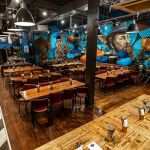 Founders & Co Swansea communal dining area with mural, long tables and relaxed seating.