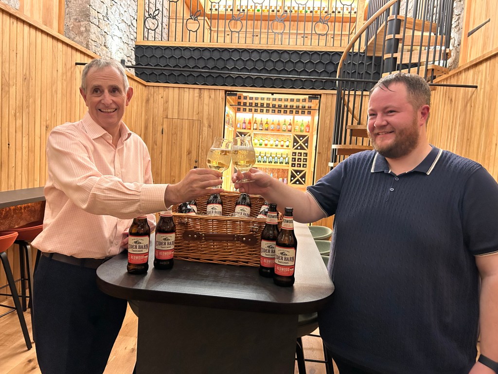 Scott Sullivan and Martin Thatcher raising glasses of cider inside the Cider Barn.
