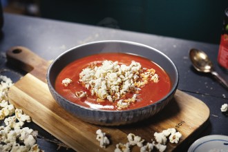 Tomato soup with salted popcorn sprinkled on top.
