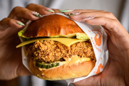 Close‑up promotional image of Popeyes fried chicken showcasing the brand’s hand‑breaded Louisiana seasoning.
