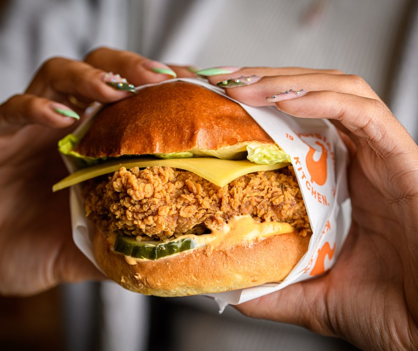 Close‑up promotional image of Popeyes fried chicken showcasing the brand’s hand‑breaded Louisiana seasoning.