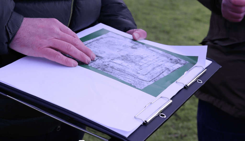 Close‑up of Dr Alex Langlands’ hands holding a geophysical survey map at Margam.