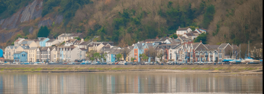Scenic view of Mumbles from across the water, showing colourful buildings along the seafront.