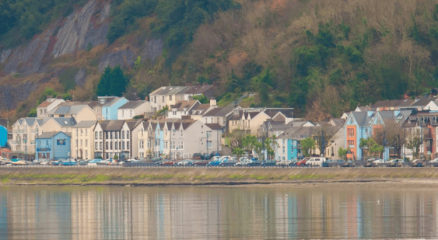 Scenic view of Mumbles from across the water, showing colourful buildings along the seafront.