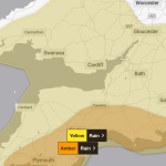 Met Office map highlighting Yellow and Amber rain warnings across South West Wales, Devon and Cornwall, with major cities and motorways labelled.