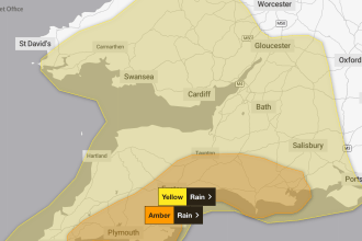 Met Office map highlighting Yellow and Amber rain warnings across South West Wales, Devon and Cornwall, with major cities and motorways labelled.