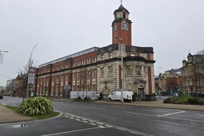 Exterior view of the wedge‑shaped former Swansea Central Police Station at Orchard Street and Alexandra Road, now refurbished as temporary accommodation.