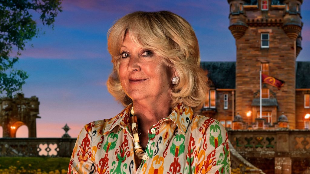 Portrait of Swansea contestant Fiona Hughes from The Traitors Series 4, smiling against a dark studio backdrop.