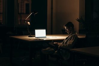 man in black and white stripe dress shirt sitting on chair in front of macbook