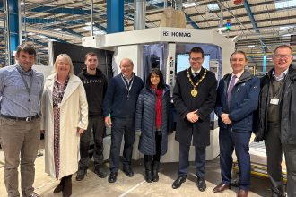 Group photo of Sigma 3 Kitchens staff and Bridgend Council representatives standing beside the new CNC drilling machine at the company’s Bridgend site.