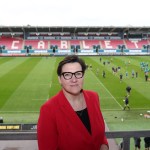 Tonia Antoniazzi standing pitchside at Parc y Scarlets with players training in the background.