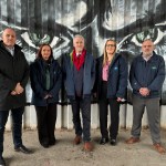 Deputy First Minister Huw Irranca‑Davies standing with council and Fly‑tipping Action Wales representatives in front of the “Don’t Waste Our Future” anti‑fly‑tipping mural created by local pupils and artist Steve Jenkins.