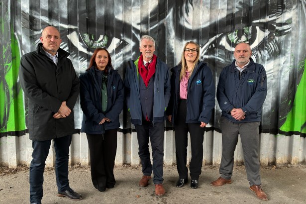 Deputy First Minister Huw Irranca‑Davies standing with council and Fly‑tipping Action Wales representatives in front of the “Don’t Waste Our Future” anti‑fly‑tipping mural created by local pupils and artist Steve Jenkins.