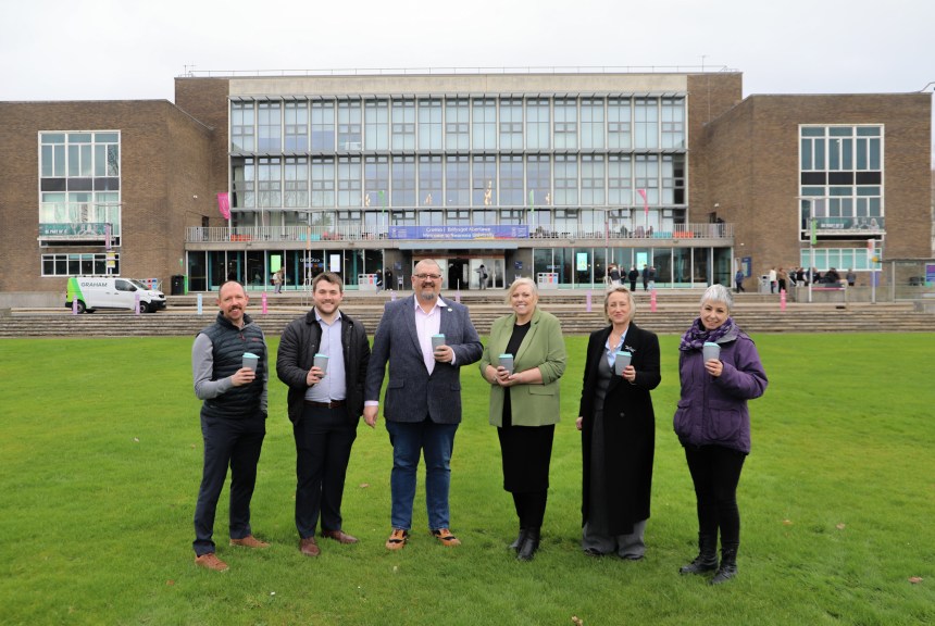 Group photo taken outside Swansea University’s main campus entrance, showing staff and quoted partners at the launch of the 2GoCup reusable cup initiative.