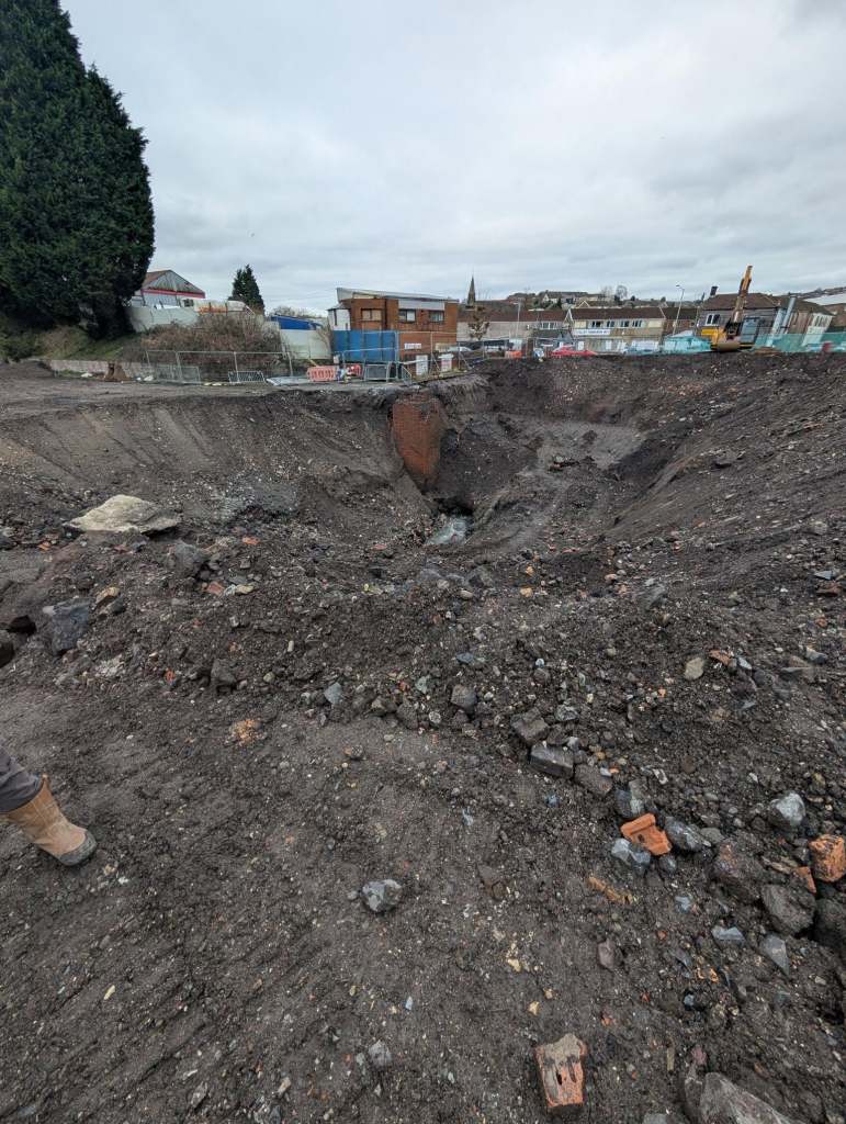 Large excavation showing exposed underground structures at the Cwmfelin sinkhole.