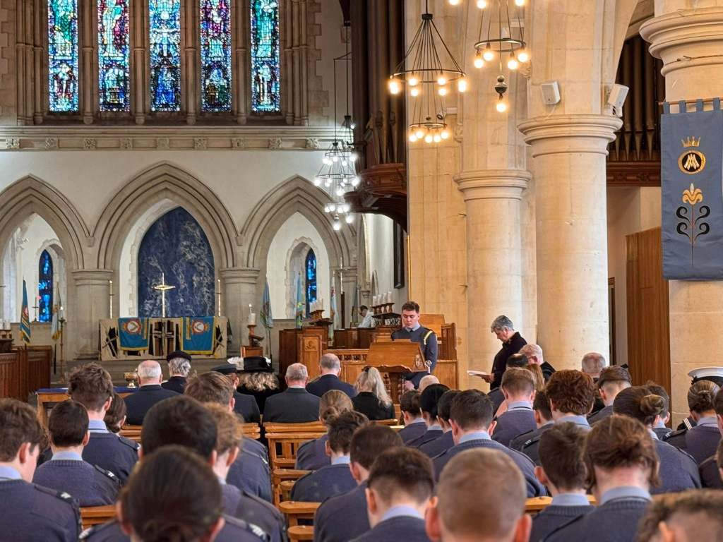 A young RAF Air Cadet stands at a lectern delivering a reading during the anniversary service at Swansea Minster.