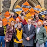 Welsh Liberal Democrat leader Jane Dodds MS with Swansea councillors Sandra Joy, Allan Jeffery and Sam Bennett in front row, surrounded by party supporters holding orange Liberal Democrat campaign signs at Brynmill Community Centre