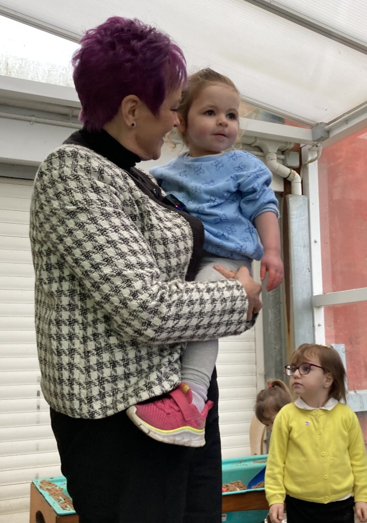 Minister Dawn Bowden holding a young child during a visit to a Flying Start childcare setting in Swansea.