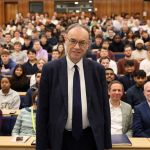 Andrew Bailey standing at the front of a full lecture hall, addressing Swansea University students during a Q&A session.