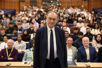 Andrew Bailey standing at the front of a full lecture hall, addressing Swansea University students during a Q&A session.