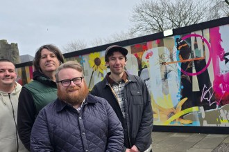 Group photo of Elliott King, artist Hasan Kamil and Oner Signs staff standing in front of the Castle Square Gardens artwork.