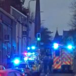 Multiple emergency vehicles with flashing lights parked on a Carmarthen street during the response to an incident, with police and ambulance crews visible.