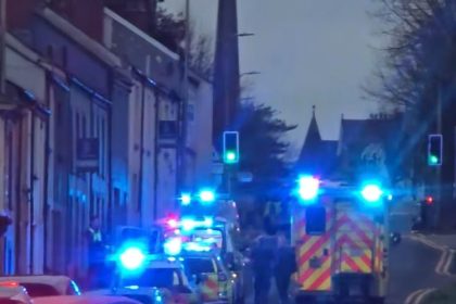 Multiple emergency vehicles with flashing lights parked on a Carmarthen street during the response to an incident, with police and ambulance crews visible.