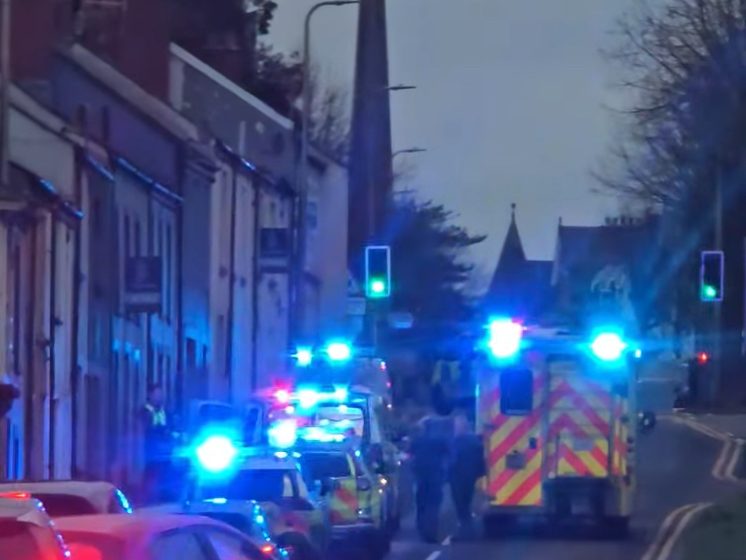 Multiple emergency vehicles with flashing lights parked on a Carmarthen street during the response to an incident, with police and ambulance crews visible.