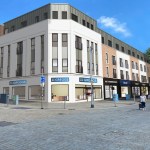 CGI rendering of the refurbished 254-260 Oxford Street building in Swansea showing modern shop frontages including Greggs bakery on the ground floor with apartments above
