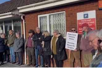 Residents forming a human chain outside Meddygfa'r Sarn surgery in Pontyates holding protest banners against its proposed closure