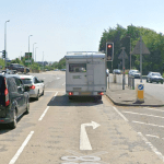 Image of the A4138 Halfway junction in Llanelli, showing vehicles at a red light, a pedestrian island, and road markings for turning lanes.