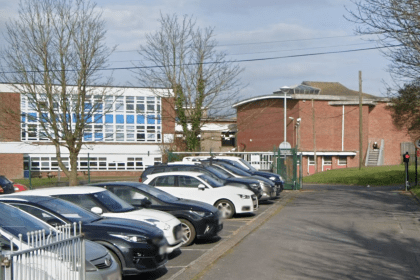 Exterior view of Milford Haven Comprehensive School with car park, gated entrance and school buildings.